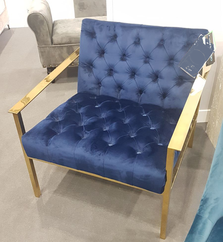 image of an arm chair which looks luxury. It has gold arms with a navy velvet seat and back.
