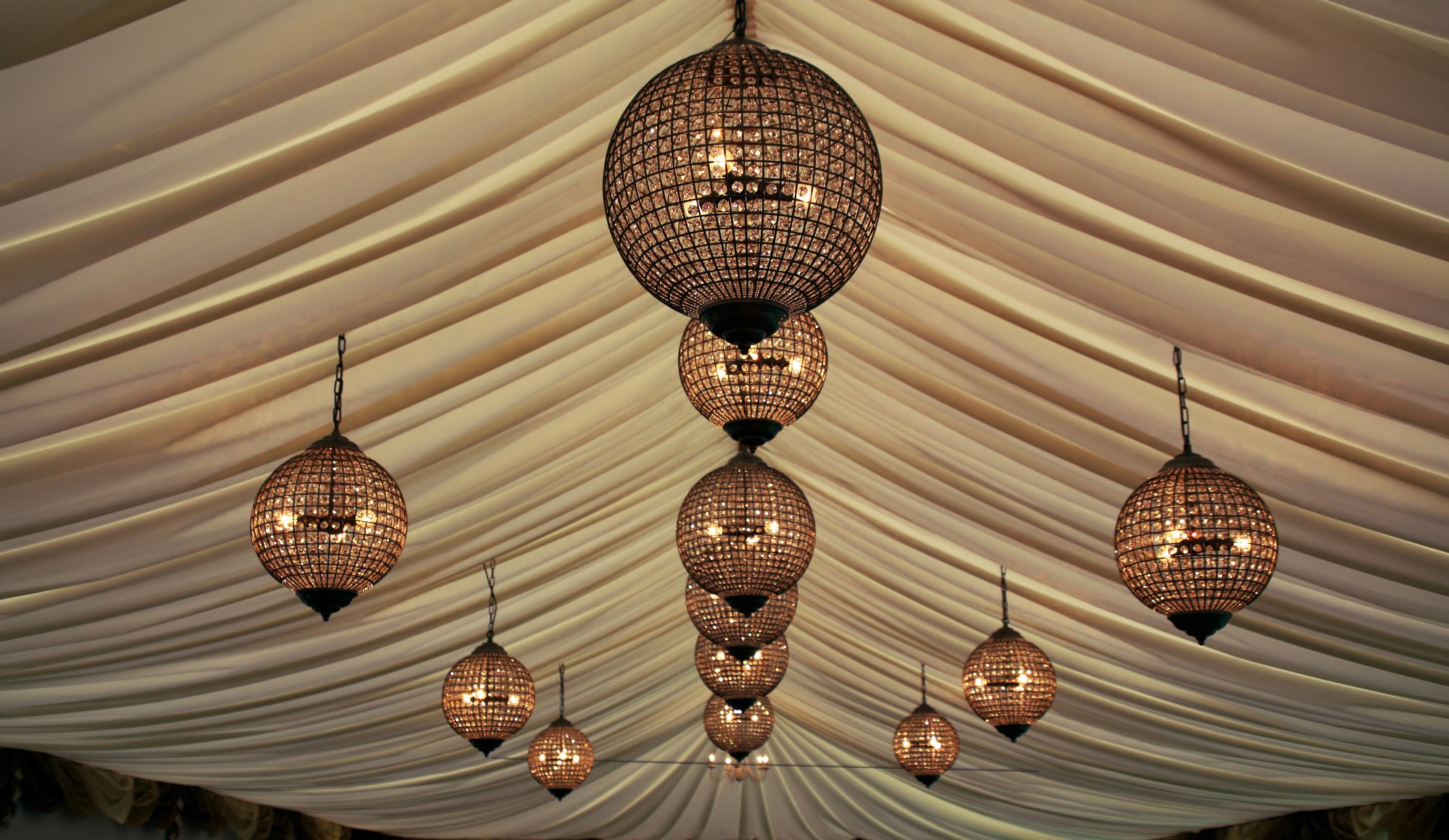 inside the white marquee with luxurious gold crystal chandeliers by Furniture on the move